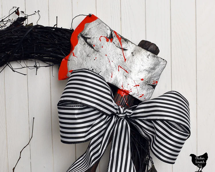 sleepy hollow inspired wreath with black and white striped bow and fake axe with blood splatter on it