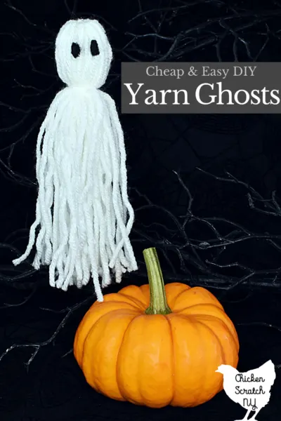 single white yarn ghost hanging from fishing line with a small orange pumpkin