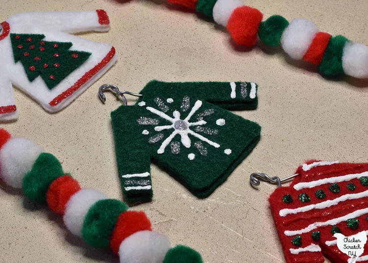 green felt ugly Christmas sweater ornament with white and silver snowflake made with puffy paint