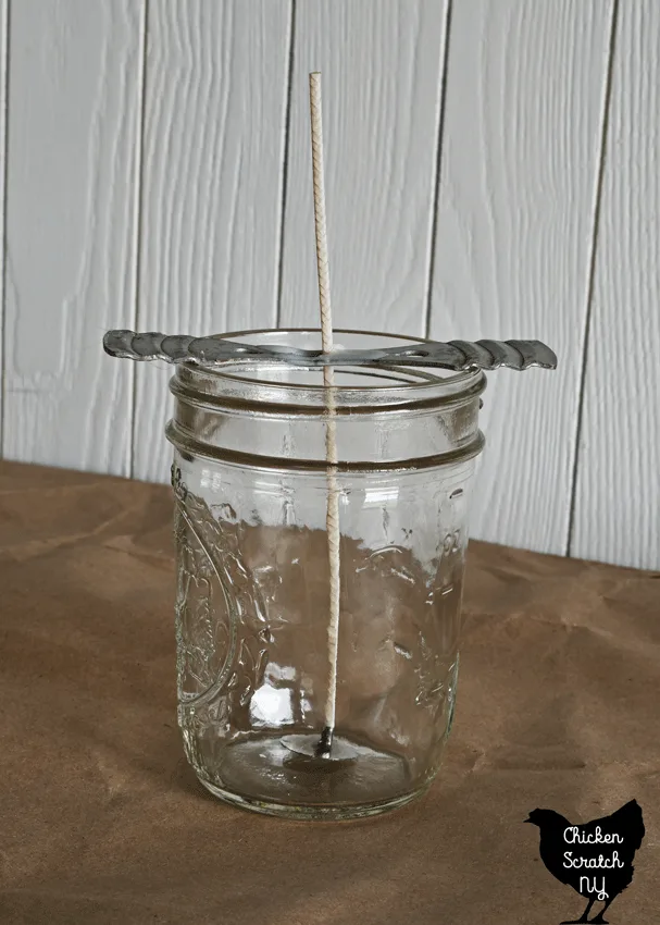 jelly jar with wick and wick holder set up to make a soy wax jar candle 