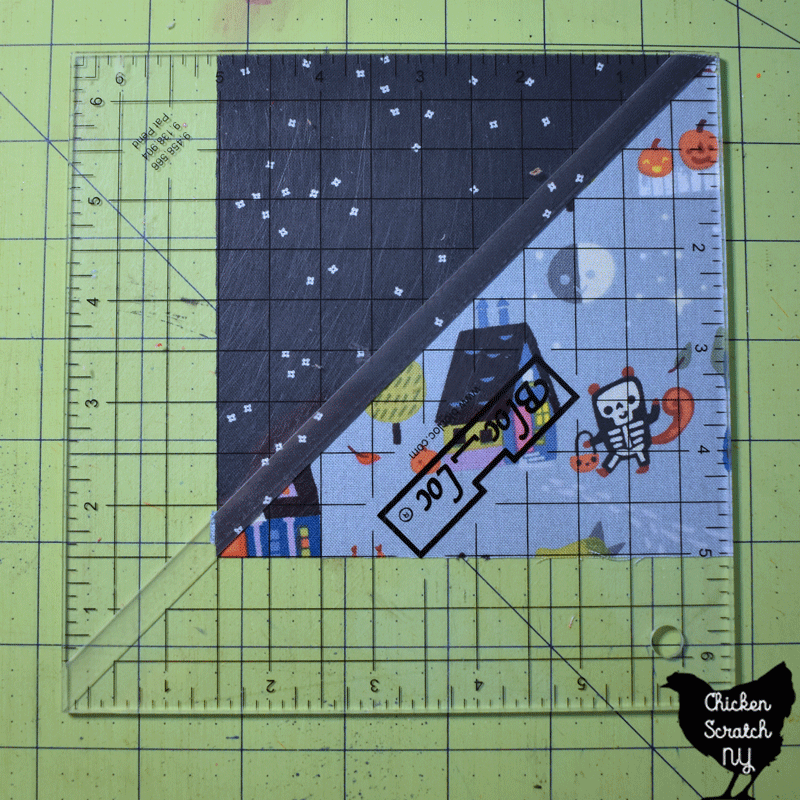 halloween fabric Half Square triangle block with BlocLoc ruler on top for squaring up