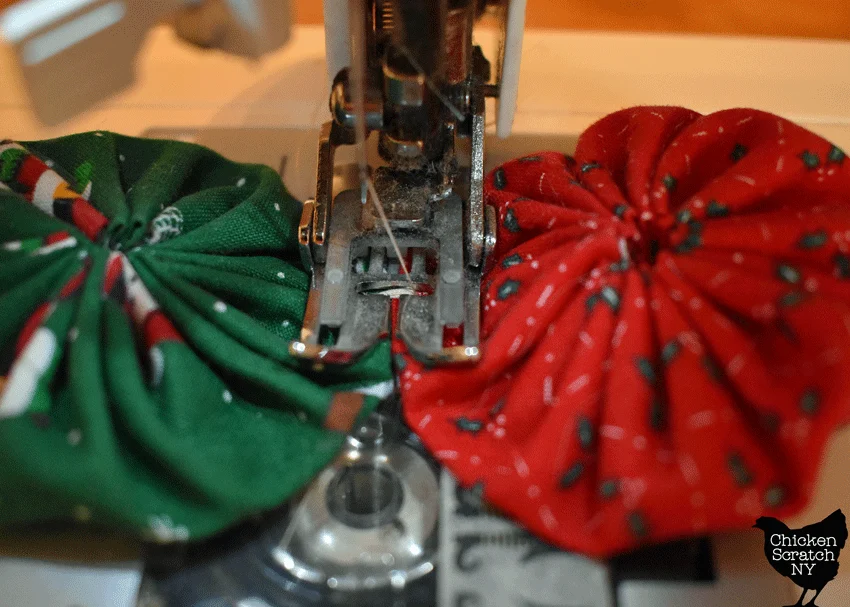 sewing machine sewing together two fabric yoyos with a wide zigzag set on a zero stitch length