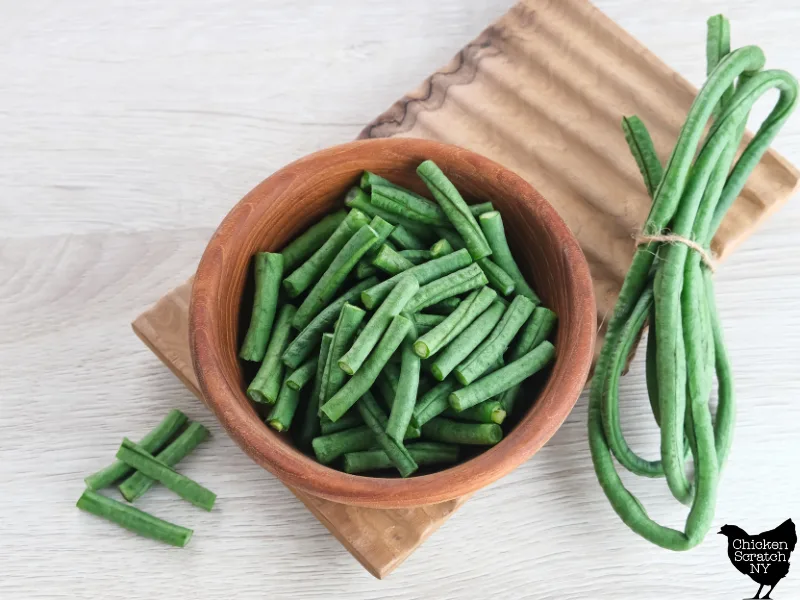 bowl filled with cut yard long beans next to a few folded full size long beans