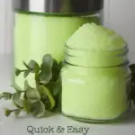 two glass jars holding lime green bath salts on a white surface