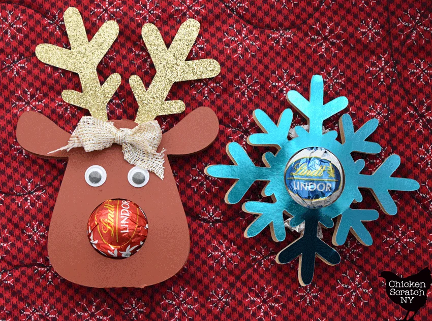 two cardstock Christmas ornaments, one reindeer with a red truffle nose and a blue snowflake with a blue truffle center