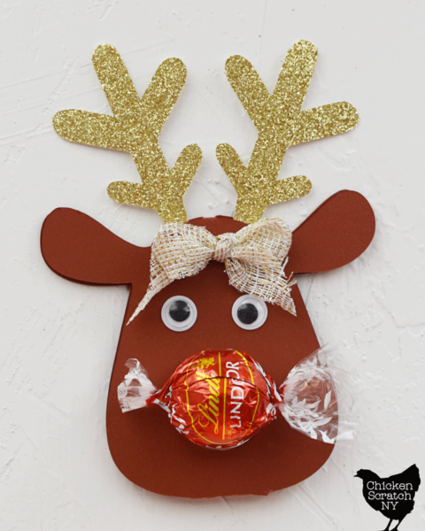 lindt truffle in red wrapper on top of reindeer ornament showing how to trim the wrapper so it doesn't stick out the sides