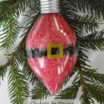 clear plastic ornament filled with red and black bath salts layered to look like Santa